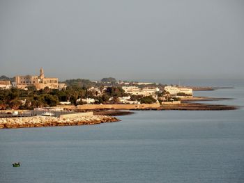 Buildings by sea against clear sky