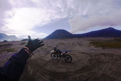 Person riding bicycle on mountain against sky