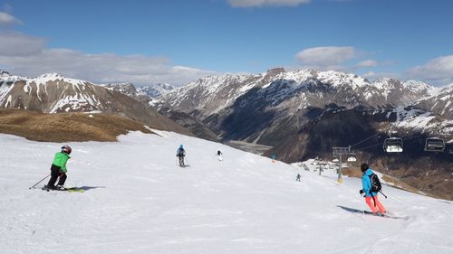 People skiing on snowcapped mountain against sky