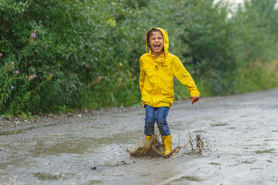 Portrait of smiling boy standing in rain