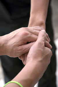 Cropped image of woman holding man hands