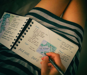 Midsection of person reading book on paper