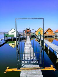 Pier over sea against clear blue sky