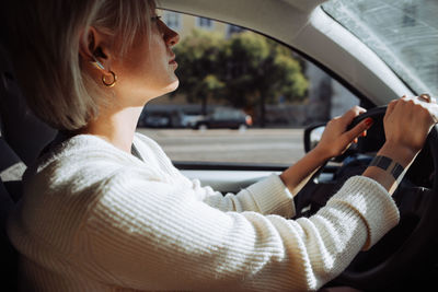 Inside view of a blond caucasian woman driving a car