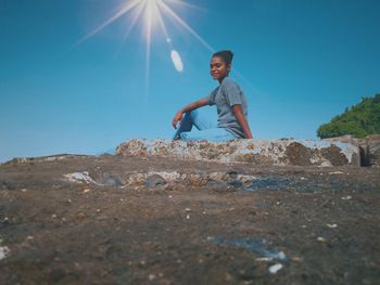 Full length of young man crouching on land against clear sky