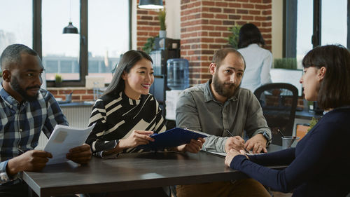 Portrait of smiling friends using laptop at office