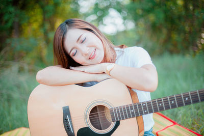 Young woman with guitar on grassy field at park