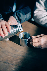 Midsection of man holding coffee cup on table