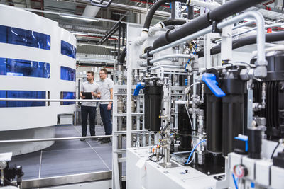 Two men looking at machine in factory shop floor