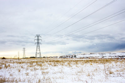 Electricity pylon on field against sky during winter