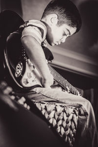 Close-up of boy playing guitar at home