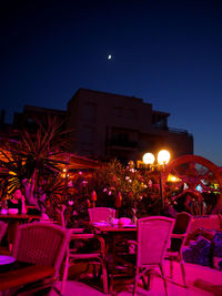 Chairs and tables at illuminated restaurant at night