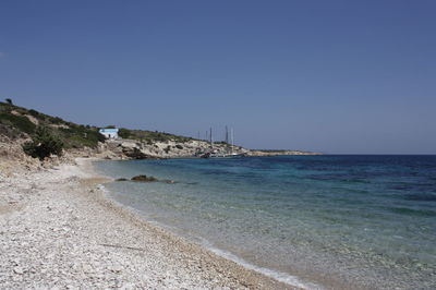 View of calm beach against clear blue sky