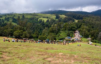 People on field by trees against sky