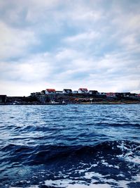 Sea by buildings in city against sky