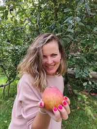 Portrait of smiling woman holding apple