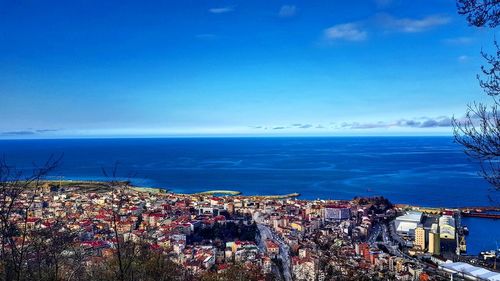 High angle view of townscape by sea against blue sky