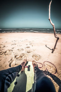 Low section of man on beach against sky
