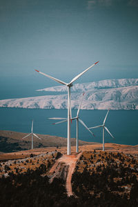 Wind turbines on sea shore against sky