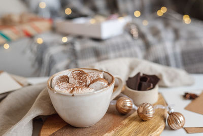 Still life with a mug of hot cocoa with marshmallows among packing materials and christmas decor.