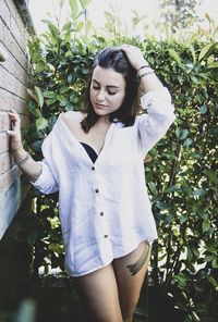 Beautiful young woman standing against plants