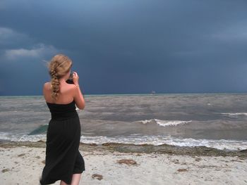 Woman standing on beach against sky