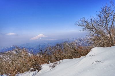 Scenic view of snow covered mountains against blue sky