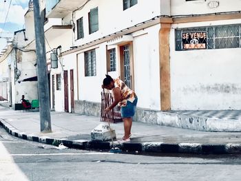 Full length of man holding umbrella on street against buildings in city