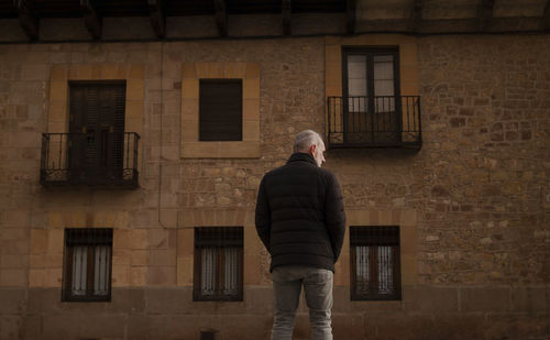 Adult man in winter clothes standing against old building. siguenza, castilla la mancha, spain