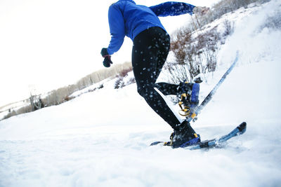 Side view of person skiing on snow covered field against sky