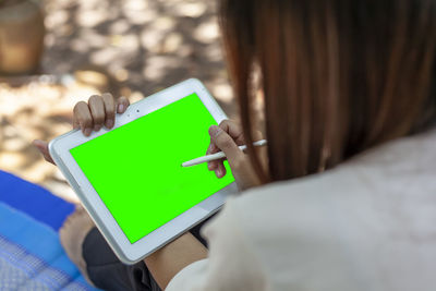 Woman's hand holding tablet and pen taking note of something with green space for text 