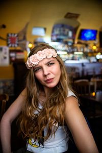 Portrait of young woman wearing flowers while standing in restaurant