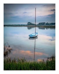 Sailboats moored in lake against sky