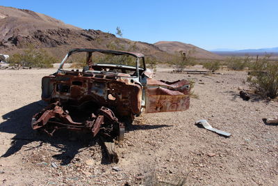 Damaged car on desert against sky