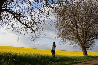 Woman standing on field against yellow sky