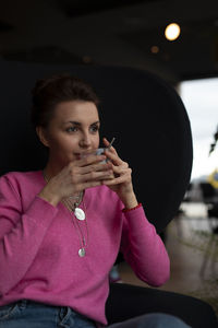 Portrait of young woman drinking water at home