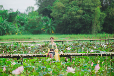Woman sitting on field by trees