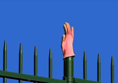 Pink kitchen glove hanging on a green metal fence
