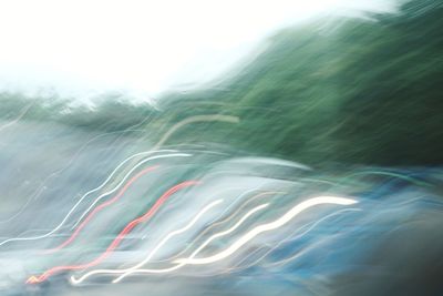 Light trails in sea against sky