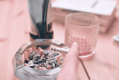 A hand holding a smoking cigarette. a hand holding a smoking cigarette. the concept of alcoholism