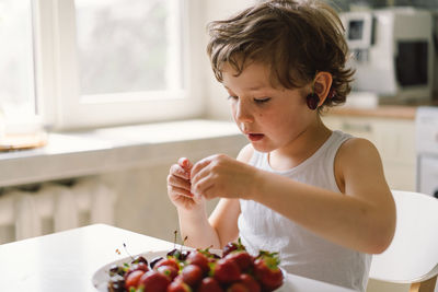 Cute beautiful little boy eating fresh cherry and strawberry.