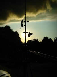 Silhouette of railroad tracks against sky during sunset