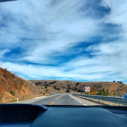 Road leading towards mountains seen through car windshield