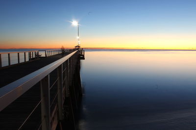 Pier over sea against sky during sunset