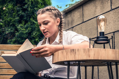 Young woman reading book in outdoor cafe