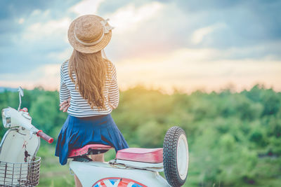 Rear view of woman sitting on motor scooter