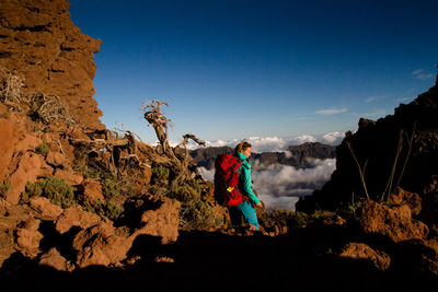 Woman walking on mountain against sky