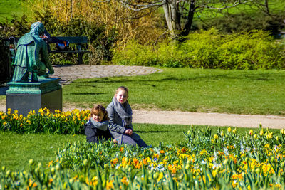 Full length of father and daughter sitting on grassy field