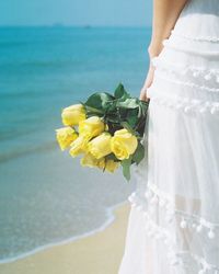 Low section of woman standing on beach by sea