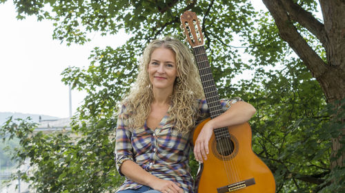 Portrait of smiling young woman against trees